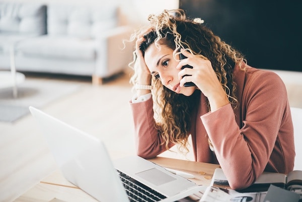 A worried woman on the phone with an attorney while looking up how long it takes to get a restraining order on her laptop