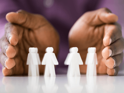 Hands symbolically show protection around figures of people